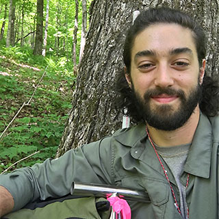 Karam Sheban, researcher of wild-simulated American ginseng, leans on the tool he uses to collect soil samples. During field research at the American Ginseng Pharm in the Catskills, he collected data on key environmental factors that contribute to the growth of healthy ginseng. Photo courtesy of Karam Sheban